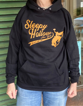 Stephanie wearing our black sleepy hollow headless horseman hooded sweatshirt with orange colored baseball logo and horseman on it.